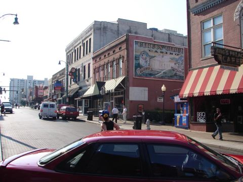 1992 Ford Taurus - A street scene unfolds with various businesses and vehicles lining the road under a bright sky.