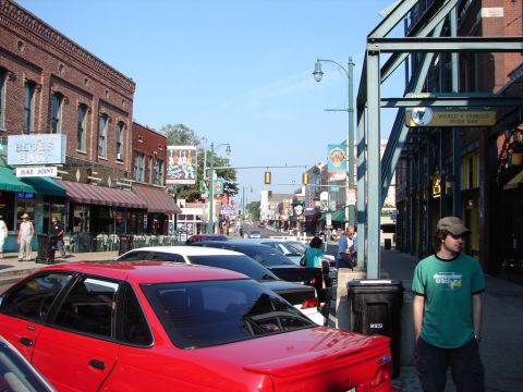 1992 Ford Taurus - A street scene in a commercial district with several cars parked along the curb.
