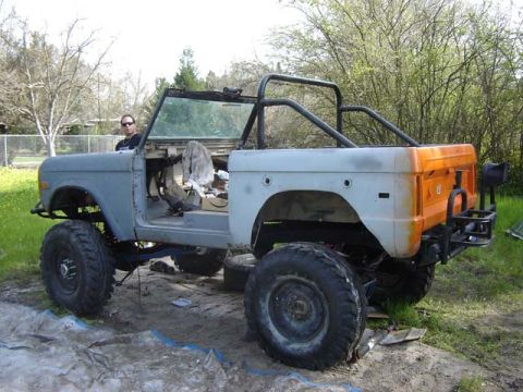 1971 Ford Bronco - A partially disassembled 1971 Ford Bronco sits outdoors, showing its frame and roll cage.