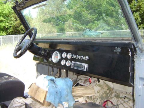 1971 Ford Bronco - The interior of a Jeep CJ shows a black dashboard with several gauges and a modern radio installed.