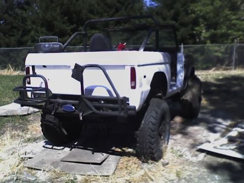 1971 Ford Bronco - White 1971 Ford Bronco with aftermarket bumpers and roll cage is parked outdoors.