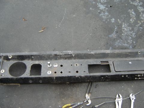 1971 Ford Bronco - A black metal dashboard panel, likely from a classic vehicle, lies on a gray surface with tools nearby.