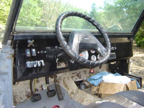 1971 Ford Bronco - The interior of a vehicle shows a worn steering wheel and a basic dashboard with gauges and switches.