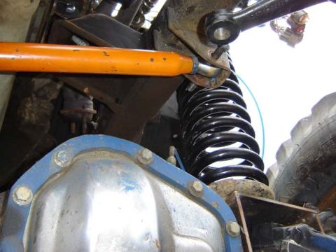 1971 Ford Bronco - Close-up view of a vehicle's suspension components, including a track bar and coil spring.