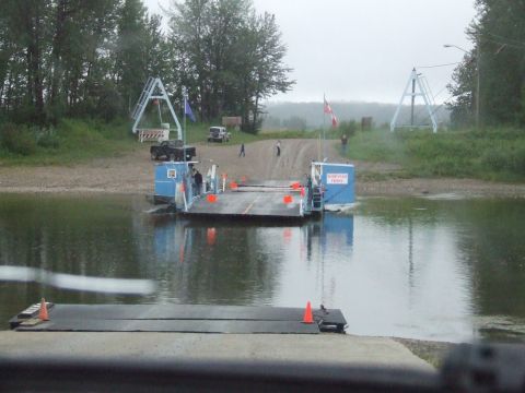 1990 Ford Bronco - A ferry transports vehicles and people across a river on a cloudy day.