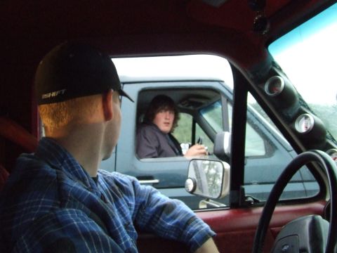 1990 Ford Bronco - Two individuals in separate vehicles make eye contact through their windows, capturing a moment of connection on the road.