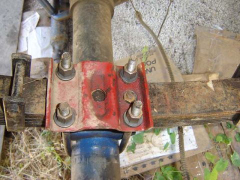 1971 Ford Bronco - Close-up view of a red leaf spring bracket attached to a vehicle's axle.