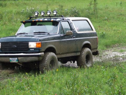 1990 Ford Bronco - This 1990 Ford Bronco is equipped for off-road adventures, seen here navigating a wet, grassy terrain.