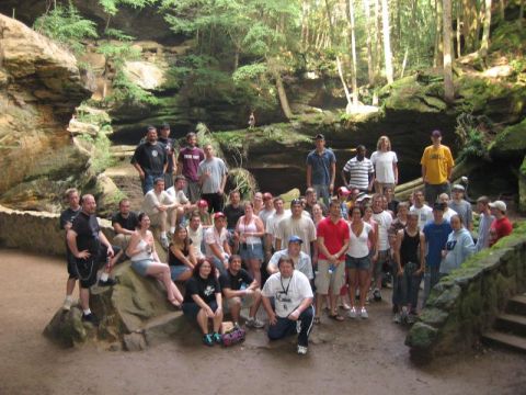 1995 Ford Probe - A large group of people gathered in a natural setting with trees and rocks.