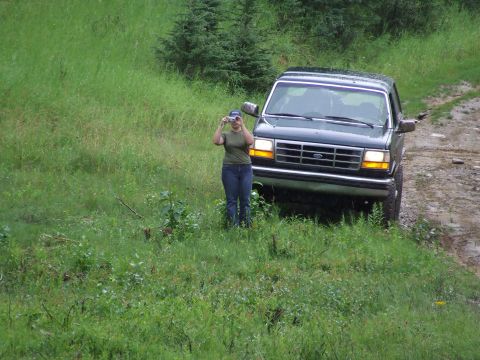1990 Ford Bronco - A person stands in front of a 1990 Ford Bronco, taking a picture of the vehicle.