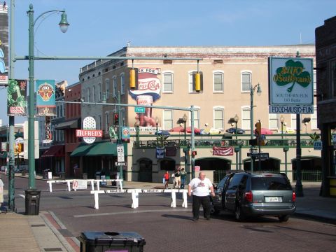 1992 Ford Taurus - A gray minivan is parked on a street with its door open, in front of buildings with advertisements.