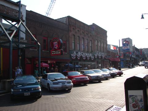 1992 Ford Taurus - A row of cars are parked along a street in front of brick buildings with various signs.