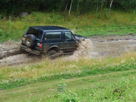 1990 Ford Bronco - 1990 Ford Bronco navigating a challenging muddy terrain.