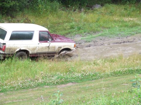 1990 Ford Bronco - Ford Bronco navigating a muddy trail during an off-road excursion.