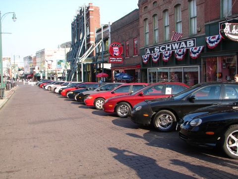 1992 Ford Taurus - A row of 1992 Ford Taurus sedans are parked along a brick street in front of storefronts.
