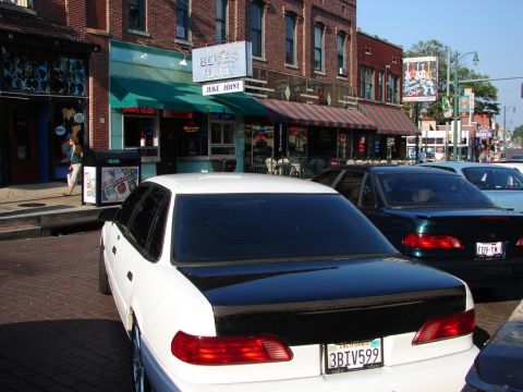 1992 Ford Taurus - White 1992 Ford Taurus with a carbon fiber trunk parked on a street in front of a blues club.
