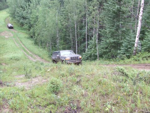 1990 Ford Bronco - Two vehicles on a dirt road in a forest, one is a 1990 Ford Bronco.