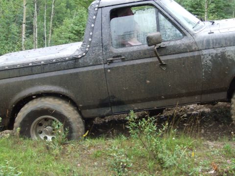 1990 Ford Bronco - This Ford Bronco is stuck in the mud while off-roading in a wooded area.
