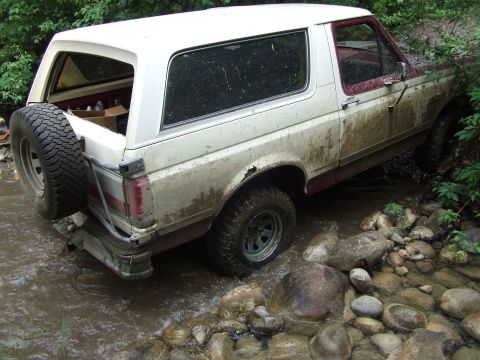 1990 Ford Bronco - This Ford Bronco appears to be from the late 1980s or early 1990s, not a 1990 model, as it navigates a challenging off-road terrain.
