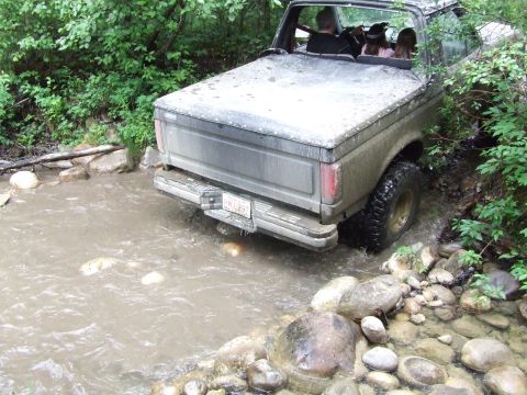 1990 Ford Bronco - This 1990 Ford Bronco navigates a rocky creek bed, its rear end visible as it splashes through the water.