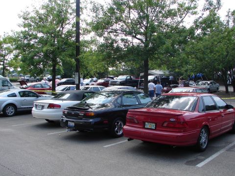 1992 Ford Taurus - A red 1992 Ford Taurus is parked at an outdoor car show with other vehicles.