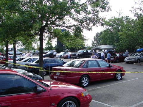 1992 Ford Taurus - A red 1992 Ford Taurus sedan is visible in the foreground at a car show event.