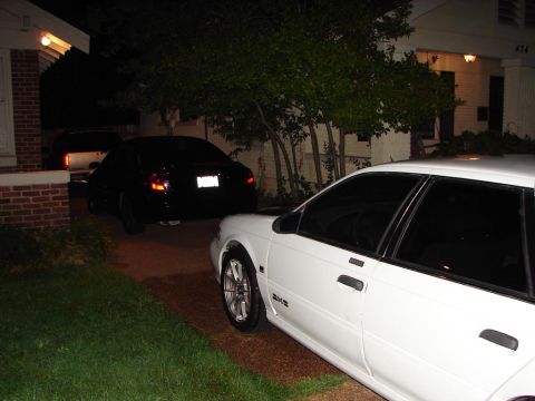 1992 Ford Taurus - A white 1992 Ford Taurus is parked in a driveway at night, with another black car behind it.