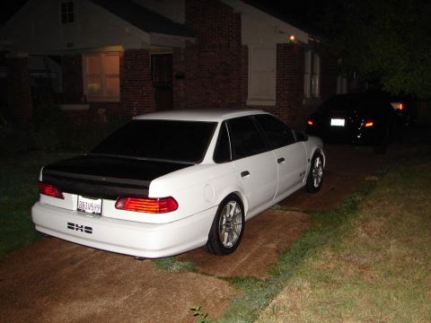 1992 Ford Taurus - Rear view of a white 1992 Ford Taurus with a black hood parked at night.