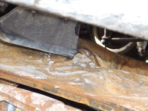 1990 Ford Bronco - Close-up view of the heavily rusted undercarriage and suspension parts of a vehicle.