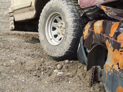 1990 Ford Bronco - Close-up of a heavily damaged and rusted vehicle fender next to a large off-road tire.