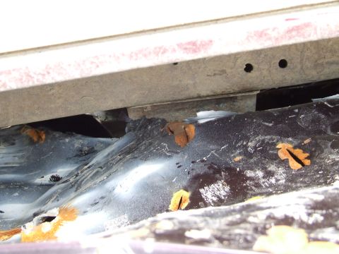 1990 Ford Bronco - The undercarriage of a vehicle shows significant rust and wear.
