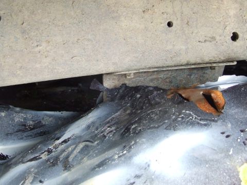 1990 Ford Bronco - Close-up view of the corroded undercarriage of a vehicle, revealing significant rust and wear.