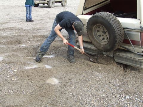 1990 Ford Bronco - A person is digging with a shovel to free a vehicle stuck in the mud.