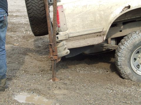 1990 Ford Bronco - Vehicle stuck in mud with a hi-lift jack being used for extraction.