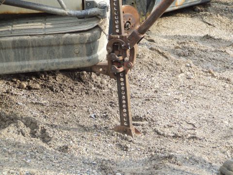 1990 Ford Bronco - A vehicle is parked on a gravel surface with a hi-lift jack attached to its side.
