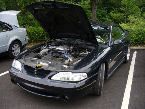 1991 Ford Probe - A black Ford Mustang is parked with its hood open, revealing the engine compartment.