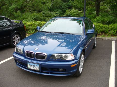 1991 Ford Probe - A blue BMW sedan is parked in a lot next to another vehicle.
