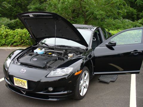 1991 Ford Probe - A black Mazda RX-8 is parked with its hood and driver's door open, revealing the engine bay and part of the interior.