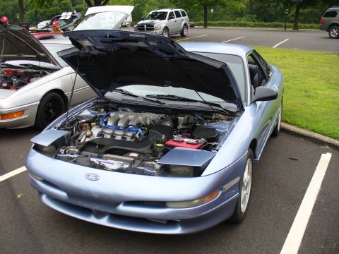 1991 Ford Probe - The front of a light blue Ford Probe is shown with its hood open, revealing the engine bay.