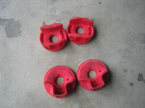1993 Ford Probe - Four red polyurethane suspension bushings are laid out on a gray concrete surface.