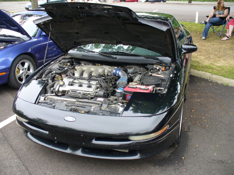 Black 1991 Ford Probe with hood open showing engine bay. Blue car parked next to it