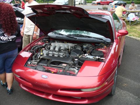 1991 Ford Probe - The engine compartment of a red 1991 Ford Probe is displayed with the hood raised.