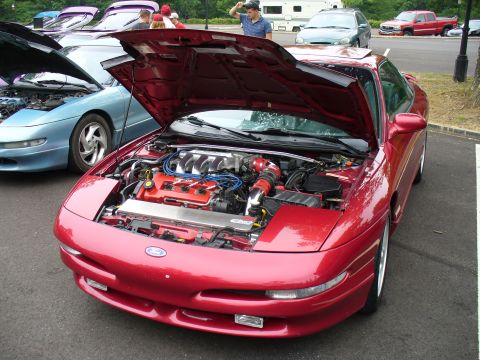 1991 Ford Probe - A red 1991 Ford Probe is displayed with its hood open, revealing the engine bay, alongside another Probe.