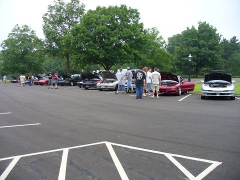 1991 Ford Probe - Several cars are parked in a lot, with people gathered around some of them.