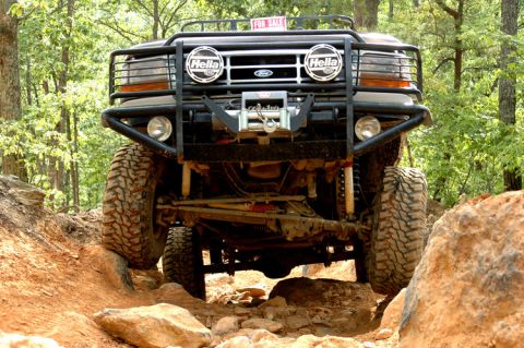 1996 Ford Bronco - Modified Ford Bronco tackling a challenging off-road trail with large tires and suspension lift.