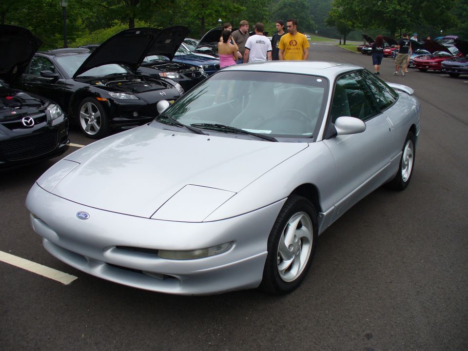 Silver 1991 Ford Probe parked at an outdoor car show with other cars around