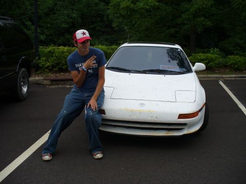 1991 Ford Probe - A man poses next to a white Toyota MR2 in a parking lot.