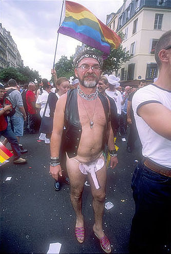 1969 Ford Mustang - A man participates in a parade, holding a rainbow flag and wearing a distinctive outfit.