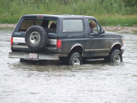 1990 Ford Bronco - 1990 Ford Bronco navigating a water crossing with its spare tire mounted externally.