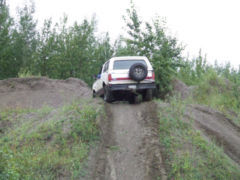 1990 Ford Bronco - White 1990 Ford Bronco navigating a challenging dirt incline off-road.